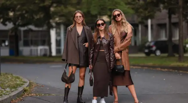 Tre donne con outfit in tonalità marroni e cammello. Un esempio di come abbinare il color cammello con capi in pelle e tessuti fluidi.