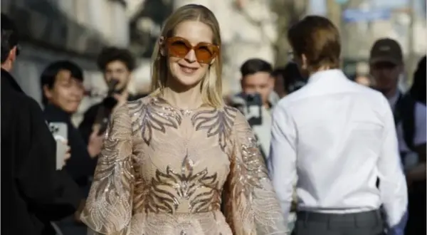 Donna con abito scintillante e occhiali da sole oversize, perfetta per un dress code cocktail donna.