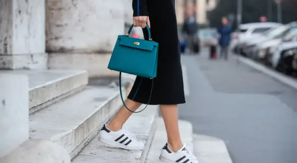 Scarpe da ginnastica bianche con strisce nere abbinate a un tubino nero e una borsa turchese.