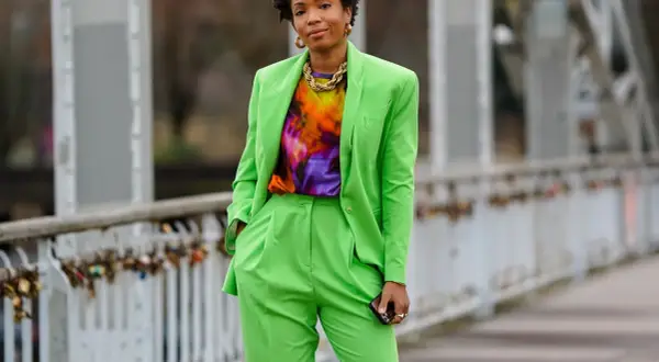 Donna con completo verde brillante, maglia tie-dye e collana dorata. Un look che celebra l'armocromia primavera con colori vivaci.