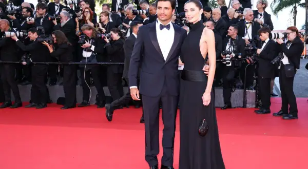 Rebecca Donaldson e il suo compagno sfilano sul red carpet, circondati da fotografi e fan.