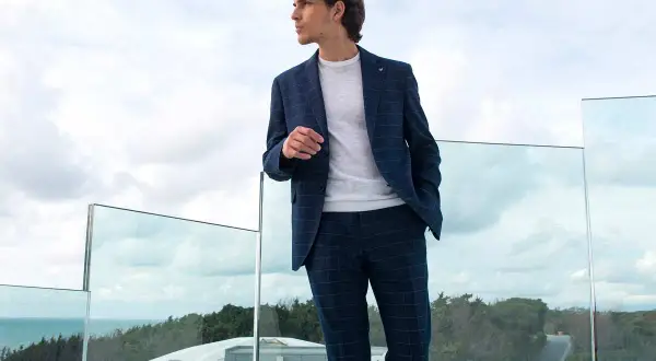 Uomo con completo a quadri blu, maglia bianca e pantaloni blu abbinamento donna.