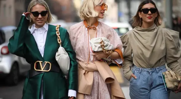 Tre donne sfoggiano un outfit pasqua alla moda: giacca verde smeraldo, abito floreale e top beige con jeans.