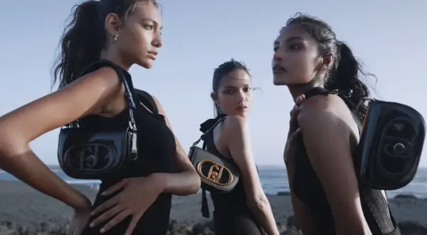 Tre modelle con borse Liu Jo, che marca è? Eleganti e moderne, posano sulla spiaggia con un look total black.