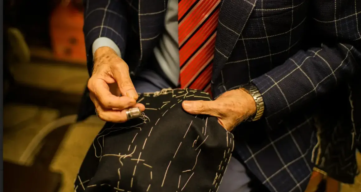 Sarto esperto cuce a mano, mostrando diversi tipi di polsini camicia. Dettagli sartoriali e precisione.