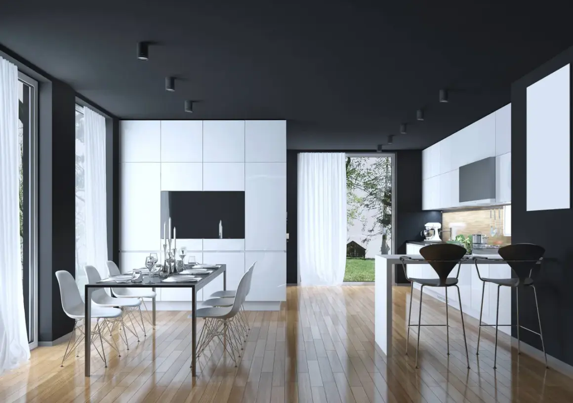 Cucina moderna con mobili bianchi lucidi, soffitto nero e pavimento in legno. Un tavolo da pranzo con sedie bianche e un'isola con sgabelli neri. Perfetti colori da abbinare al bianco e nero.