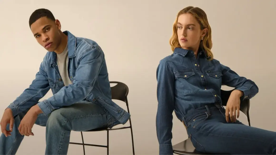 Coppia in total look denim. Lui con giacca e jeans, lei con camicia e jeans, entrambi con un fit che si stringe verso il basso, il tapered fit significato.
