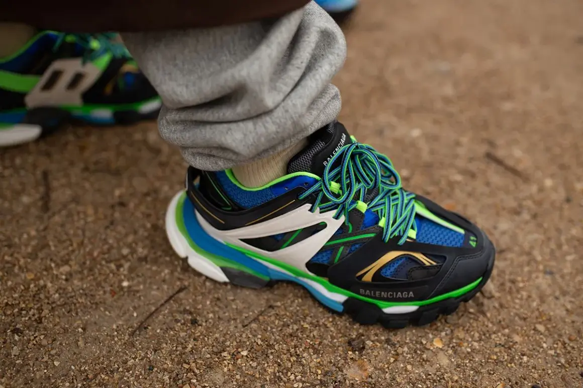 Sneaker Balenciaga con suola chunky, significato di stile audace e comfort. Lacci verdi vivaci su nero, blu e bianco.