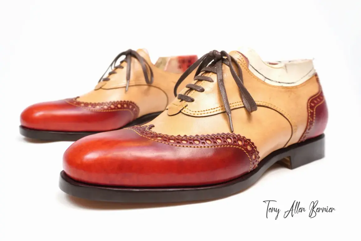 Scarpe Oxford bicolore con tomaia in pelle chiara e inserti rossi. Dettagli traforati e cuciture a vista.