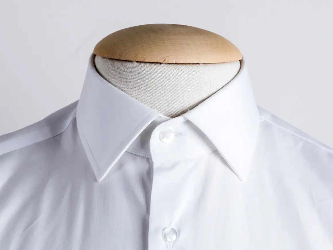Dettaglio di una camicia bianca su manichino, che mostra i diversi tipi di collo camicia.
