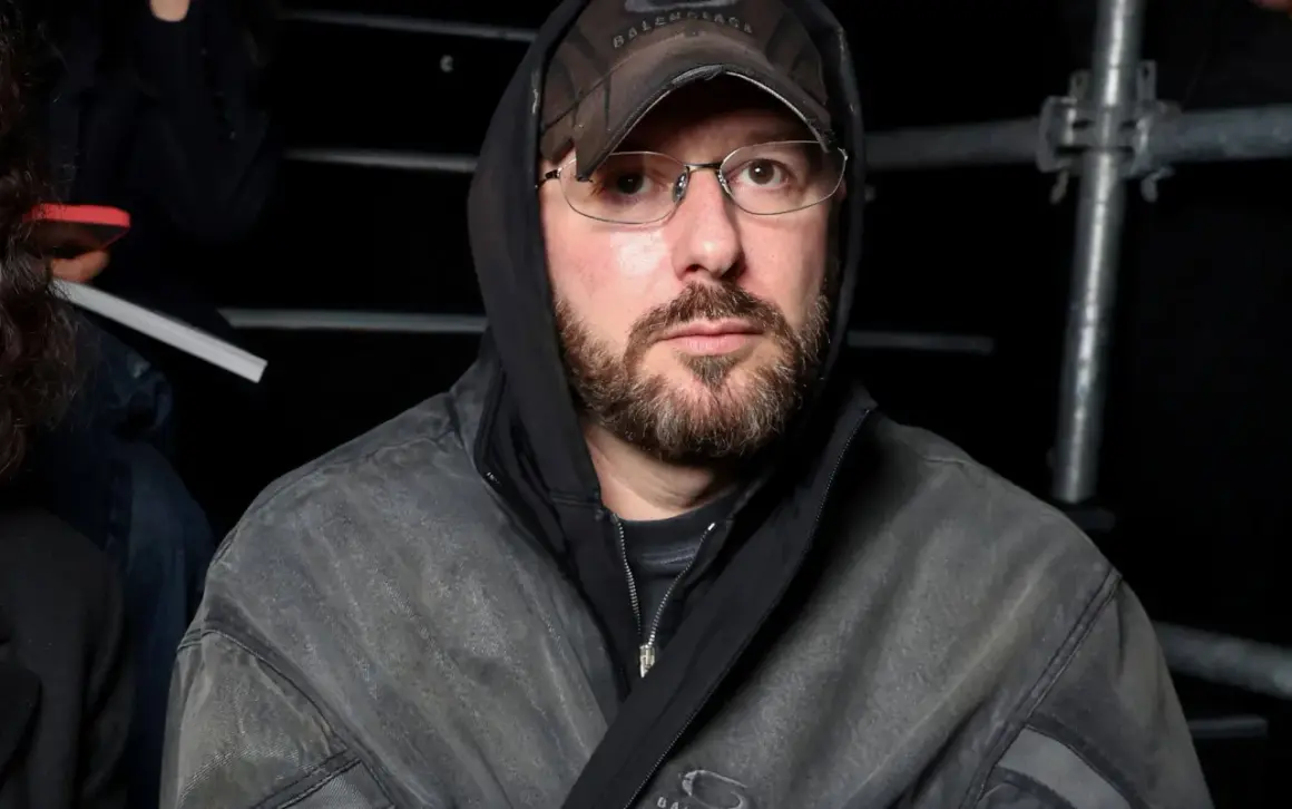 Uomo con cappuccio e cappellino Balenciaga, occhiali e barba, pronto per la sfilata Gucci.