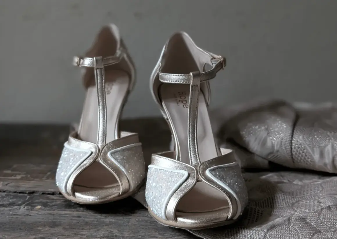 Scarpe dorate con glitter e cinturino a T, perfette da abbinare a un abito in pizzo per un look da cerimonia.