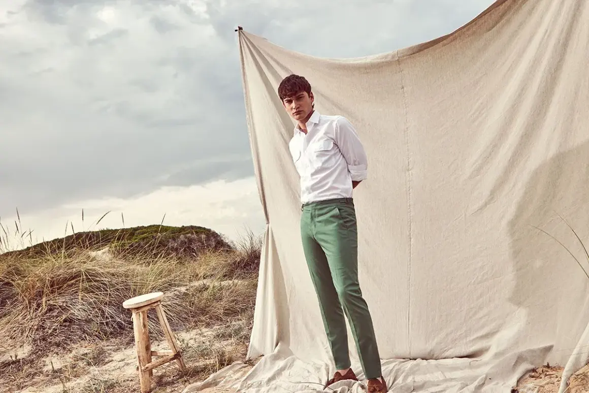 Uomo con pantaloni verdi abbinamento perfetto per un look casual chic sulla spiaggia.