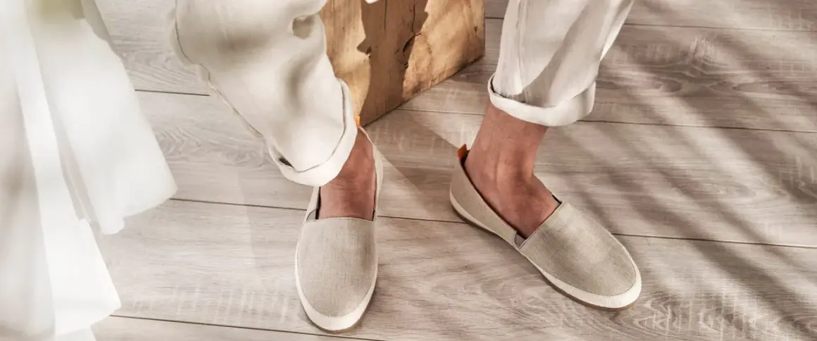 Un uomo indossa un outfit casual con espadrillas uomo in lino beige, pantaloni chiari e un dettaglio in tessuto bianco.