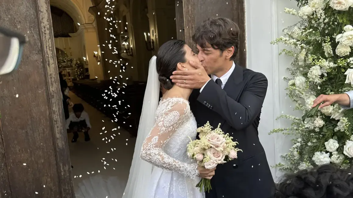 Alessandra Mastronardi e il suo sposo si baciano fuori dalla chiesa, tra petali di fiori e un'atmosfera di gioia per il loro matrimonio.