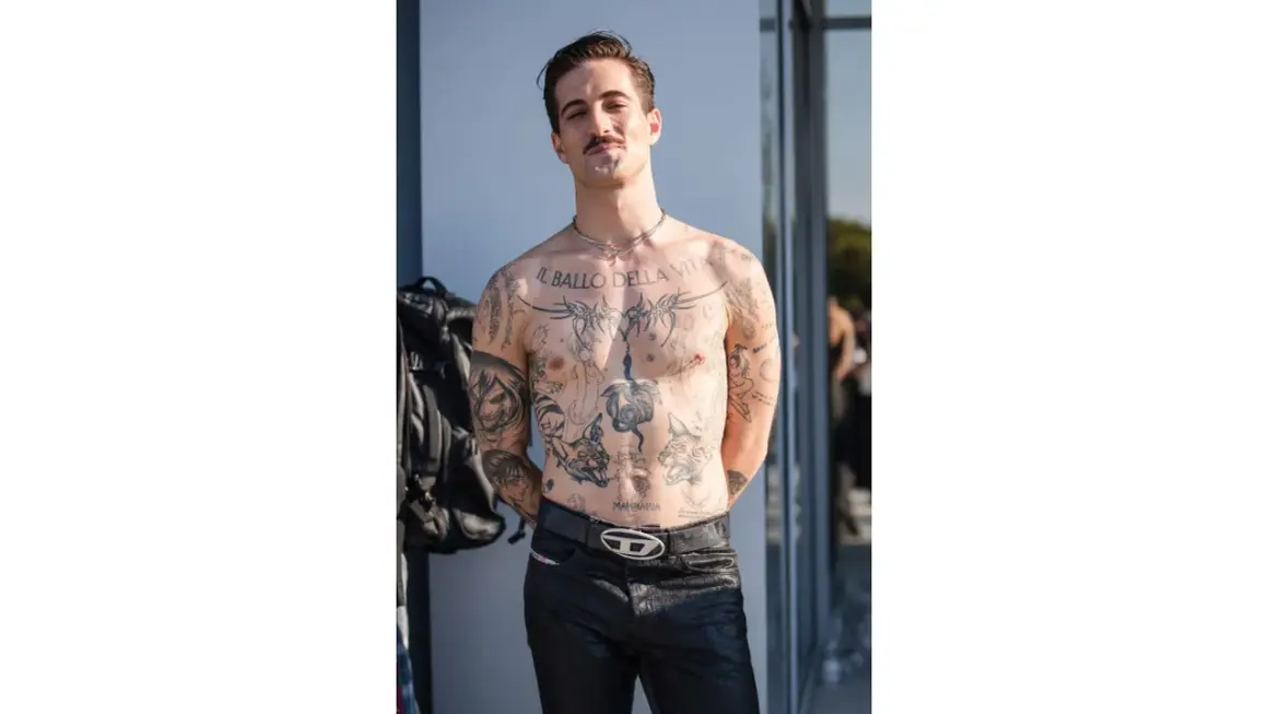Damiano David, a torso covered in tattoos, poses confidently.