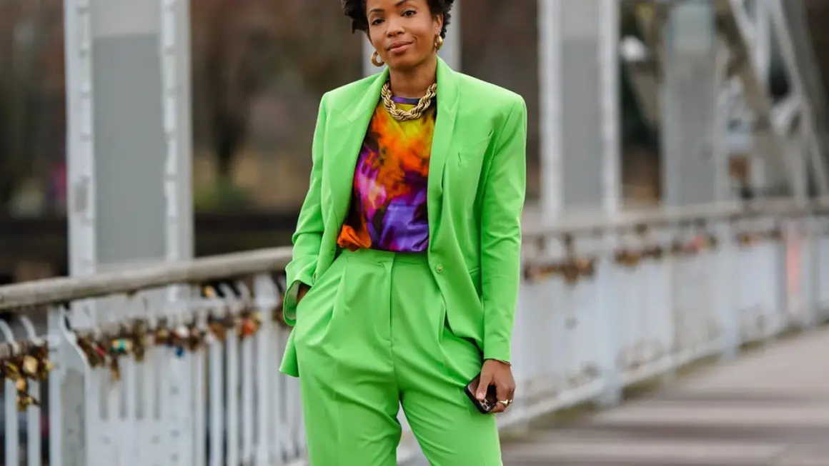 Donna con completo verde brillante, maglia tie-dye e collana dorata. Un look che celebra l'armocromia primavera con colori vivaci.