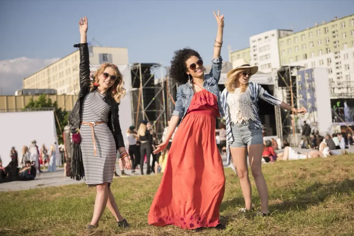 Tre amiche festeggiano a un concerto estivo: abiti leggeri, giacche e cappelli per sapere come vestirsi ad un concerto estate.