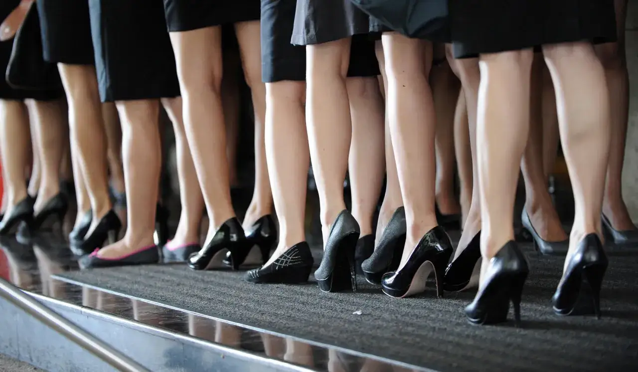 Diverse scarpe per caviglie grosse, con tacchi alti e ballerine, indossate da donne in abiti neri.
