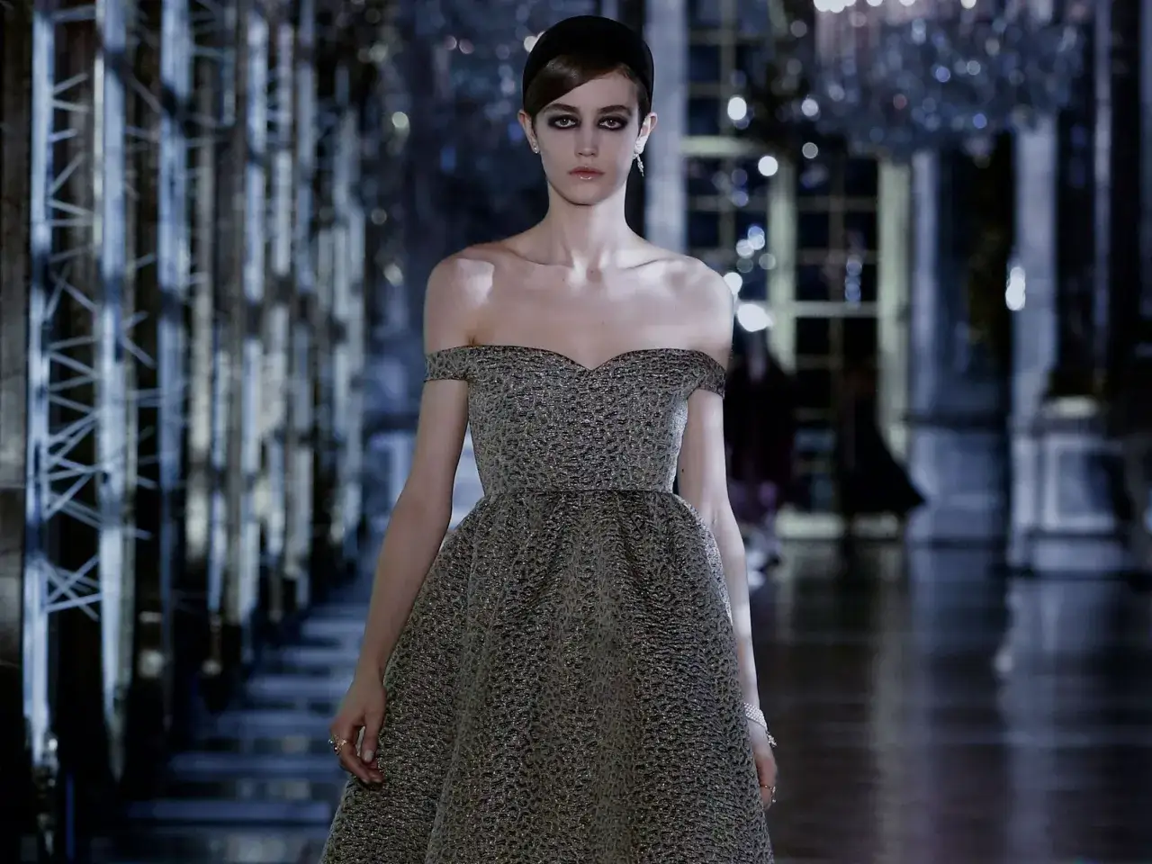 Modella con abito da sera scintillante, perfetto per un dress code cocktail donna, sfila su una passerella elegante.
