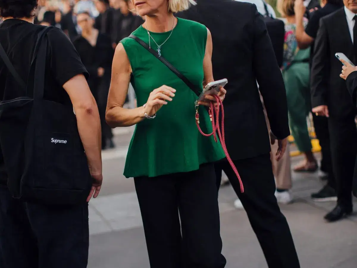 Donna con top verde bottiglia e pantaloni neri, un esempio di come abbinare il verde bottiglia con stile.