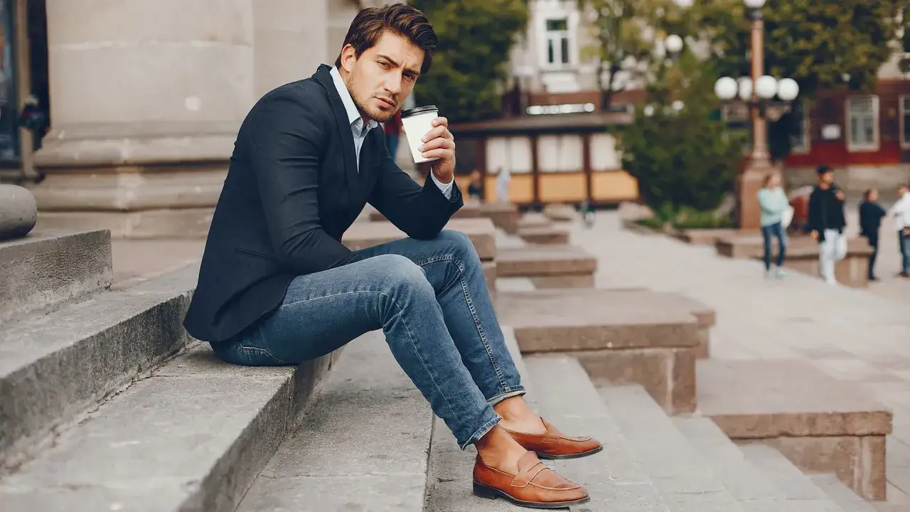 Uomo con giacca blu, jeans e mocassini marroni uomo abbinamento perfetto per un look casual chic.