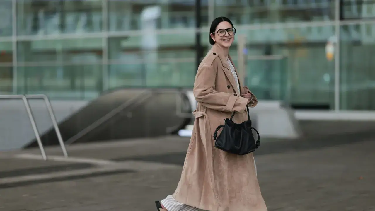 Donna con occhiali oversize e un elegante cappotto color cammello, uno dei tanti tipi di cappotto perfetti per l'autunno.