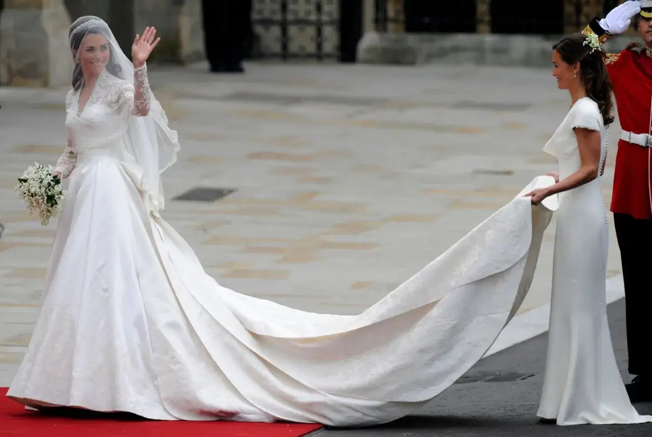 Kate Middleton sposa, con un abito da sposa da favola e un lungo strascico, saluta la folla.