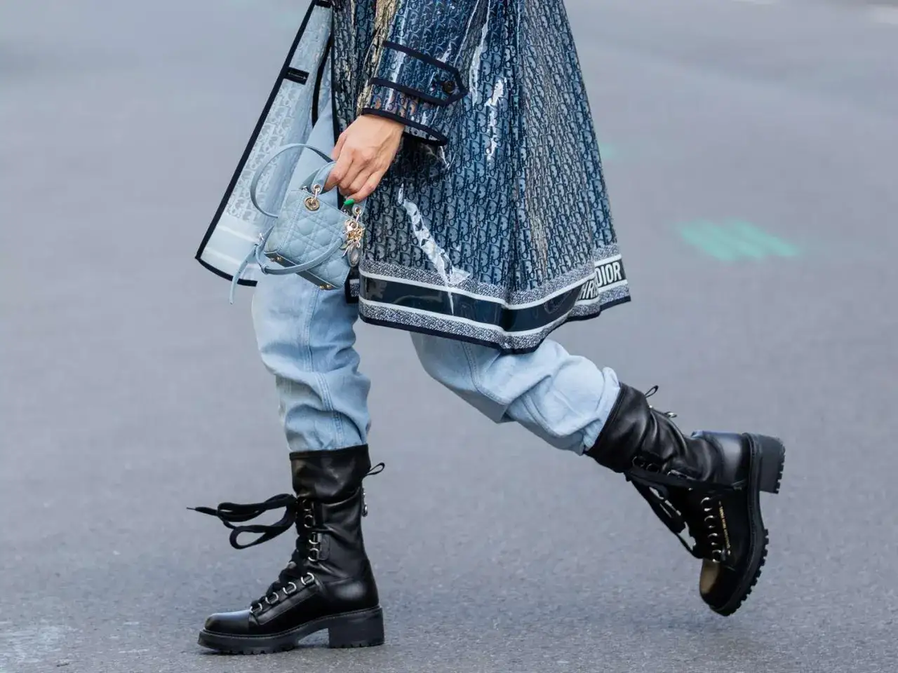 Outfit con anfibi donna: jeans chiari, trench Dior logato e mini borsa azzurra. Stile audace e chic.