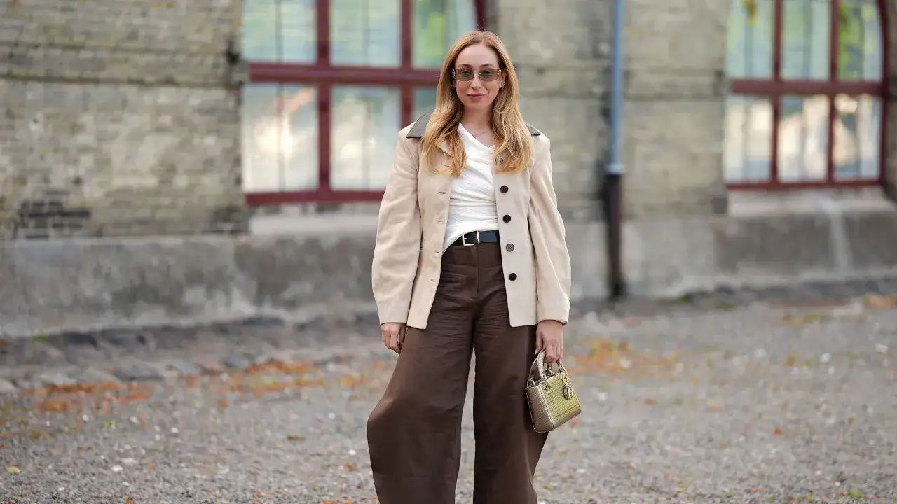 Moda chic: come abbinare il marrone con un blazer beige e accessori dorati. Pantaloni ampi e borsa piccola completano il look.