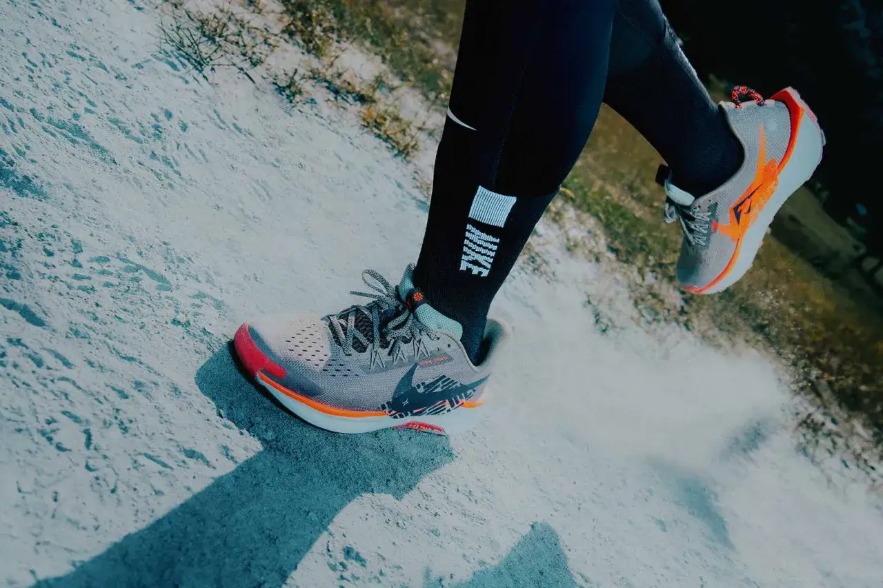 Scarpe da trail running Nike grigie e arancioni, con calzini neri e logo Nike. Perfette per ogni avventura, che sia grande o piccola.