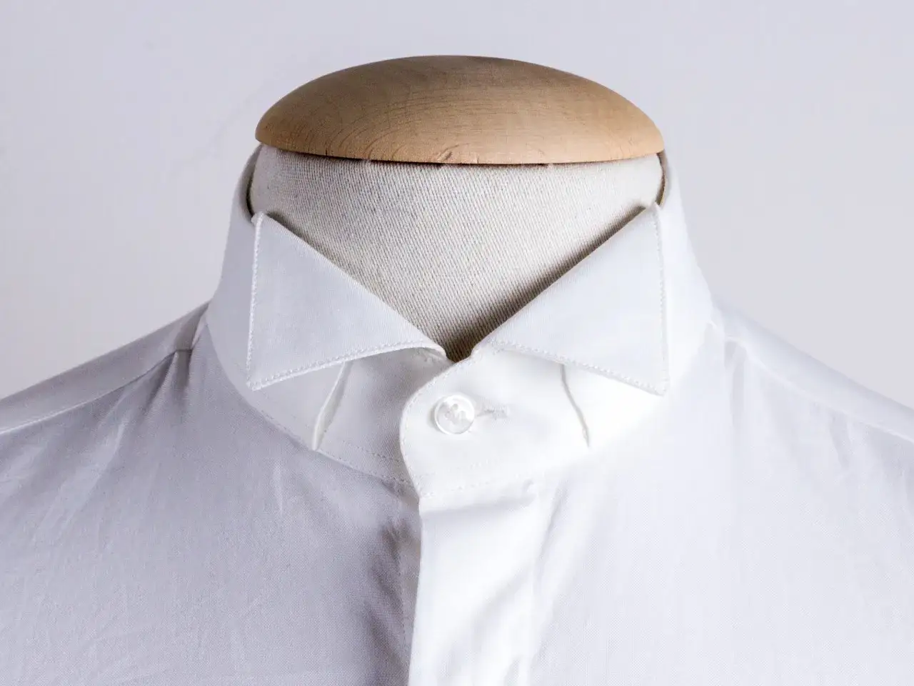 Dettaglio di una camicia bianca su manichino, che mostra i diversi tipi di collo camicia.