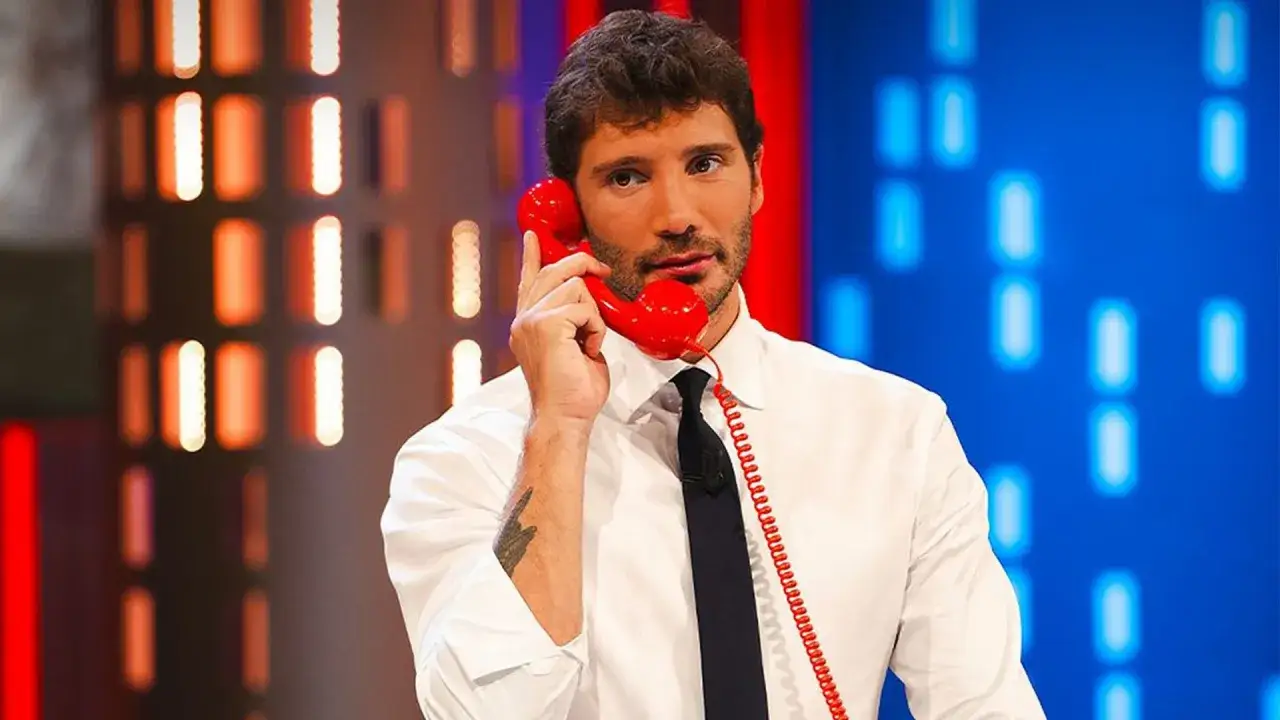 Stefano De Martino outfit: camicia bianca e cravatta nera, al telefono rosso.