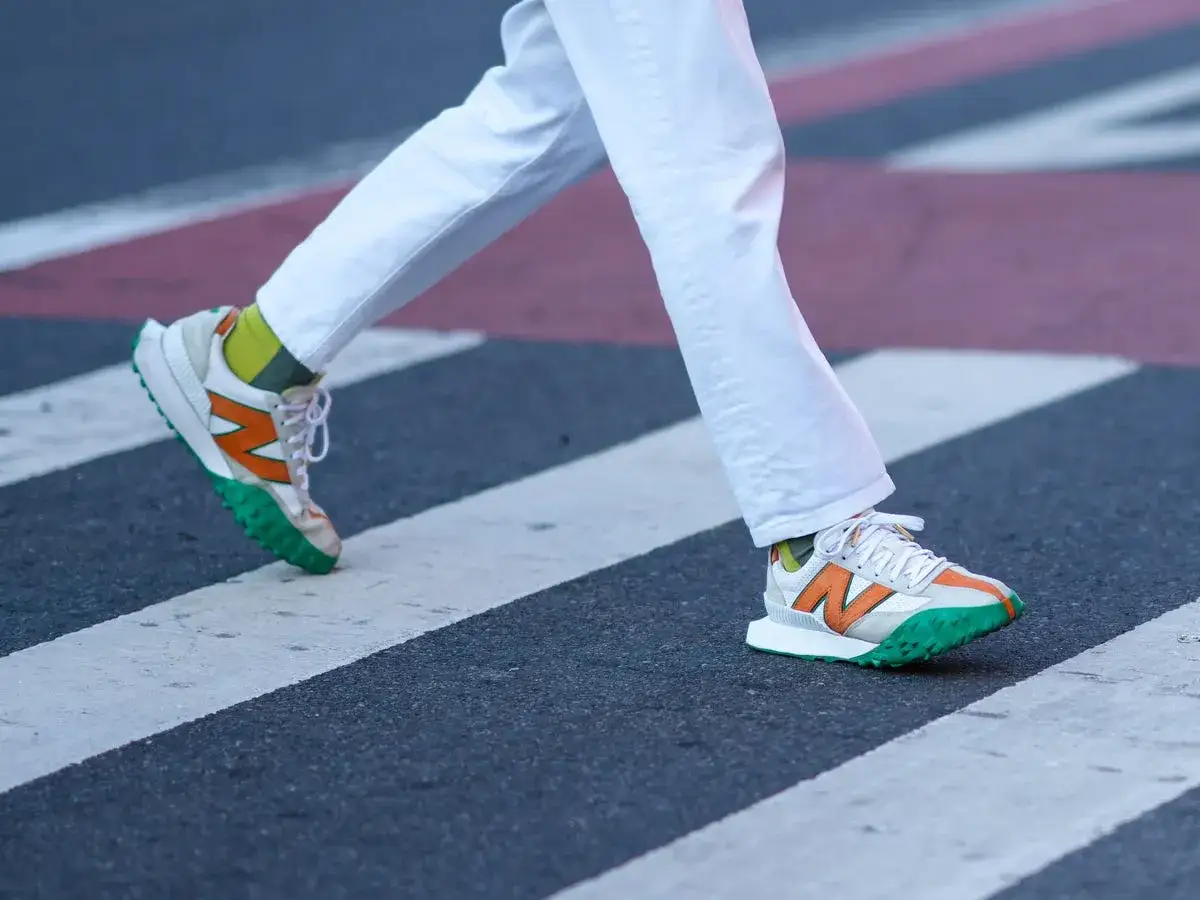Passi sicuri su strisce pedonali con sneakers New Balance colorate. L'azienda è sinonimo di stile e comfort.