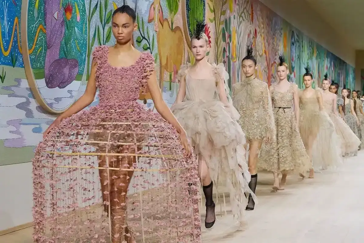 Sfilata di alta moda con abiti voluminosi e decorati, un tripudio di tessuti pregiati che incarnano l'essenza delle marche costose.
