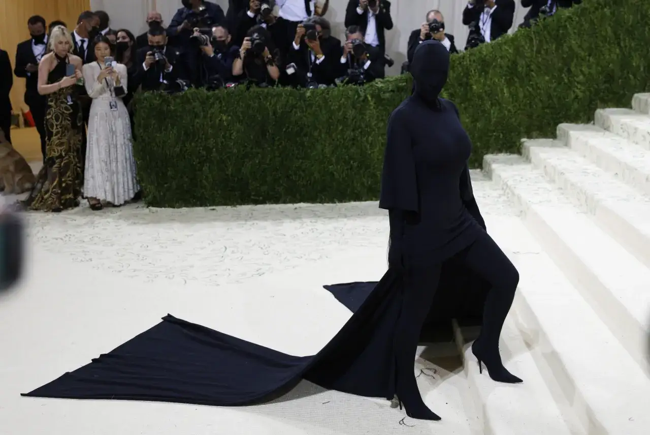 Kim Kardashian al Met Gala, avvolta in un abito nero che copre tutto il corpo, con un lungo strascico.