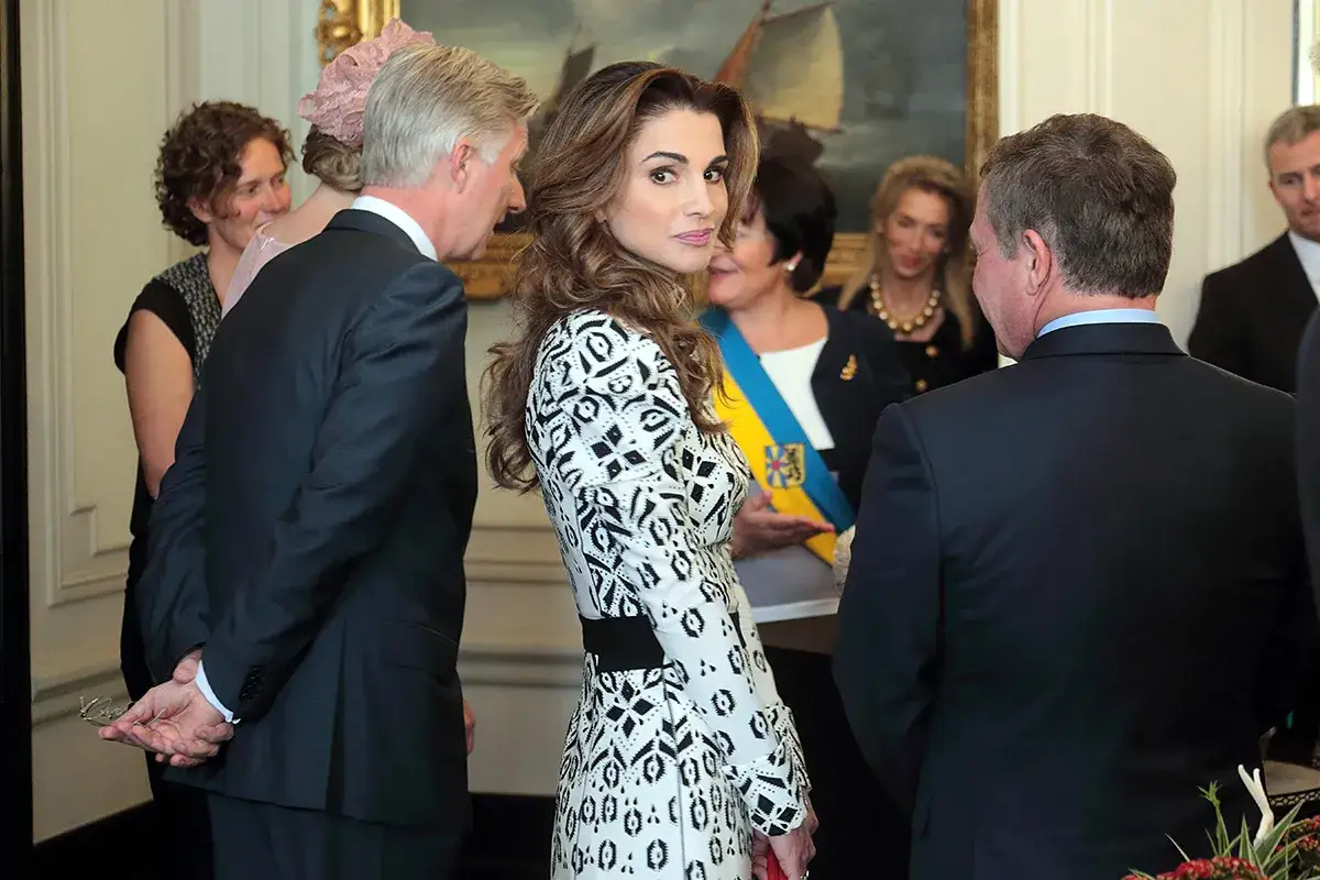 Regina Rania di Giordania, elegante in abito bianco e nero, partecipa a un evento.