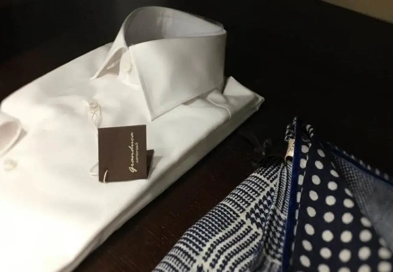 Camicia bianca da uomo con abbottonatura maschile impeccabile e pochette a pois e fantasia.