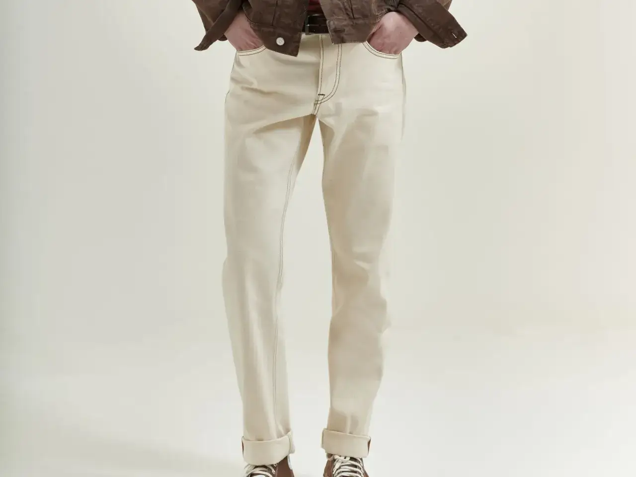 Uomo con giacca marrone e jeans chiari. La vestibilità è più rilassata, mostrando la differenza tra skinny e slim.