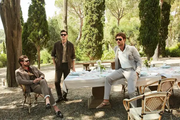 Tre uomini eleganti in un giardino. Il significato dei pantaloni chino è evidente nel loro stile casual-chic, perfetto per un pranzo all'aperto.