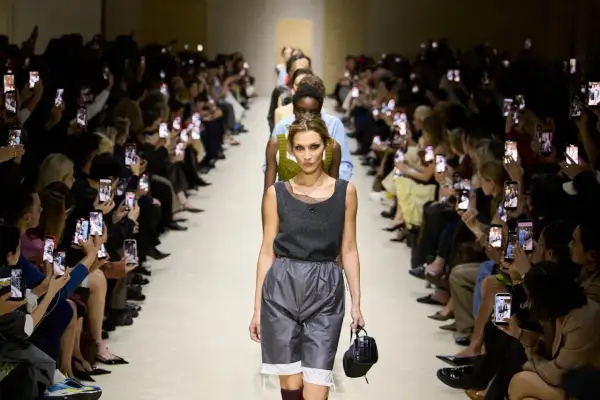 Modella sfila alla Milano Fashion Week 2026, pubblico filma con smartphone.