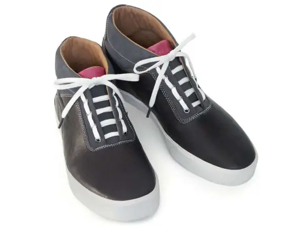 Scarpe sportive nere con lacci bianchi e dettagli grigi. Un esempio di come i lacci scarpe modi possano trasformare un look classico.