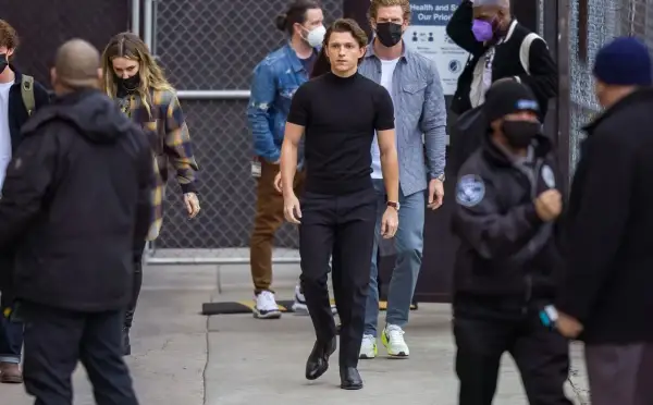 Tom Holland indossa un outfit elegante con scarpe perfette per pantaloni a sigaretta donna, mentre cammina con un gruppo di persone.