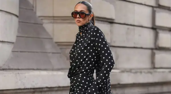 Donna con vestito a pois nero e bianco, occhiali da sole oversize. Come abbinare scarpe a questo look?