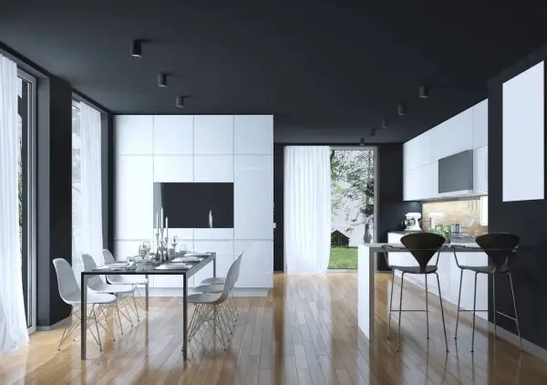 Cucina moderna con mobili bianchi lucidi, soffitto nero e pavimento in legno. Un tavolo da pranzo con sedie bianche e un'isola con sgabelli neri. Perfetti colori da abbinare al bianco e nero.