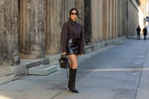 Donna con gonna di pelle e stivali alti neri, un look audace. Perfetto per capire che scarpe abbinare con una gonna di pelle.