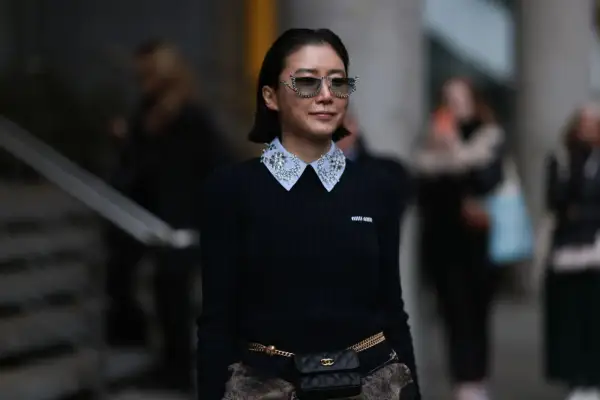 Donna con maglione nero e colletto di camicia bianco decorato con strass, un esempio di diversi tipi di colletto camicia donna.