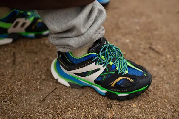 Sneaker Balenciaga con suola chunky, significato di stile audace e comfort. Lacci verdi vivaci su nero, blu e bianco.