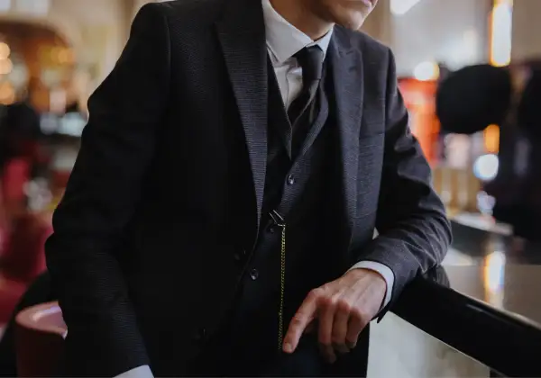 Uomo con completo gessato scuro, gilet e cravatta, un vero esempio di stile italiano.