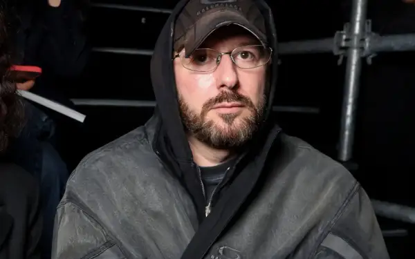Uomo con cappuccio e cappellino Balenciaga, occhiali e barba, pronto per la sfilata Gucci.